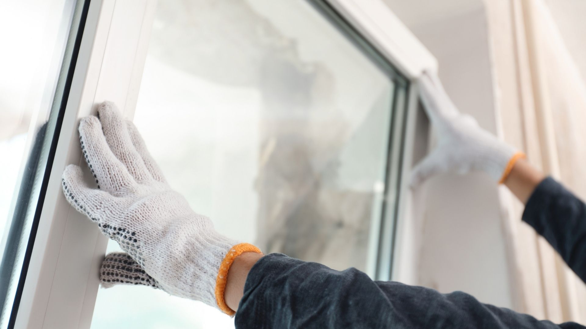 Hands in white gloves installing a window frame.