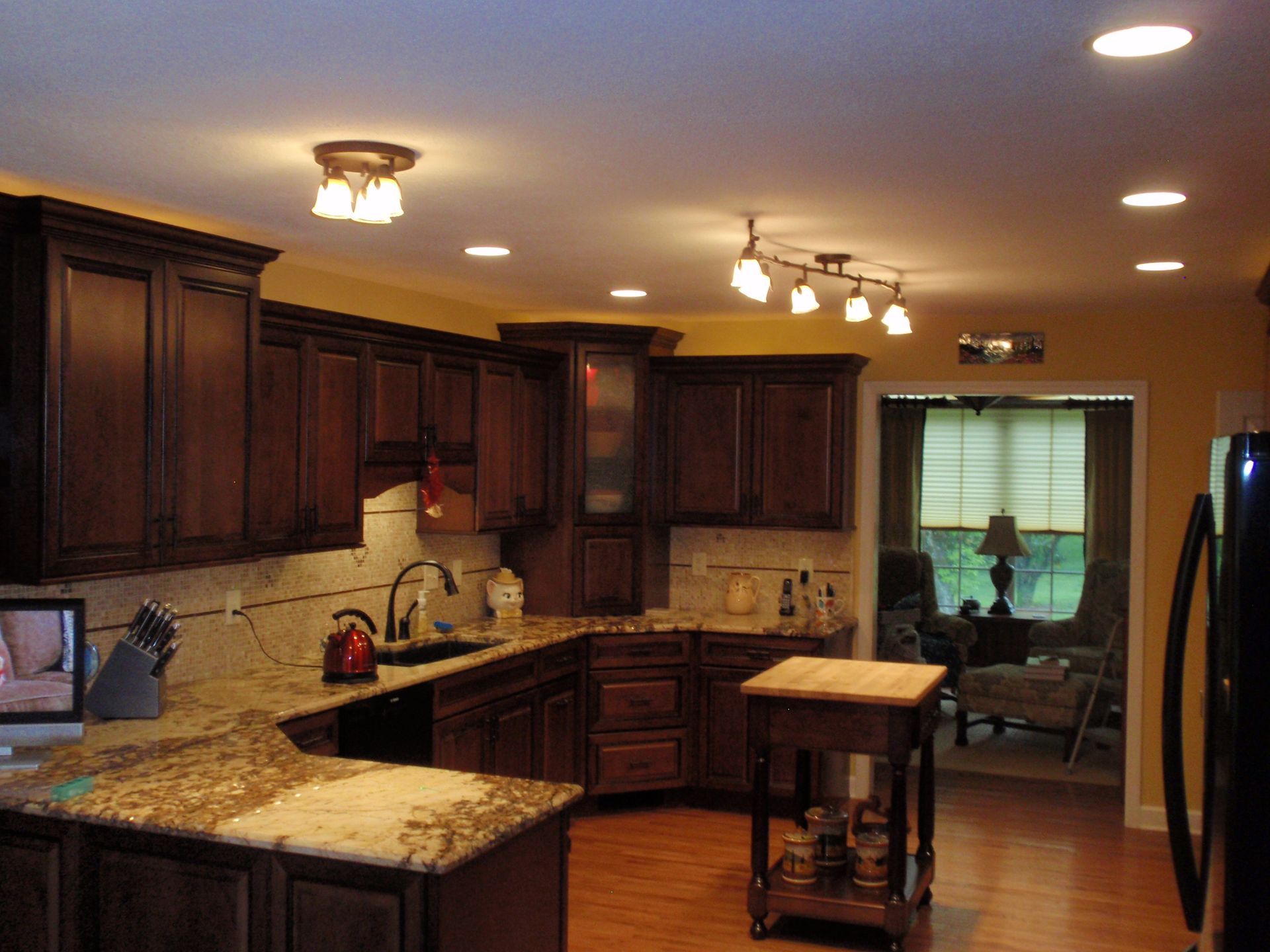 Kitchen with dark brown cabinets, granite countertops, wood floors, and recessed lighting.