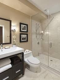 Bathroom with a glass shower, toilet, sink, and dark vanity. Beige walls and tiled shower.