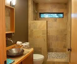 Small modern bathroom with tan tile, shower, toilet, and wooden vanity.