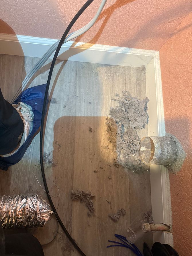 Wood floor with debris, ductwork, and a person's leg.