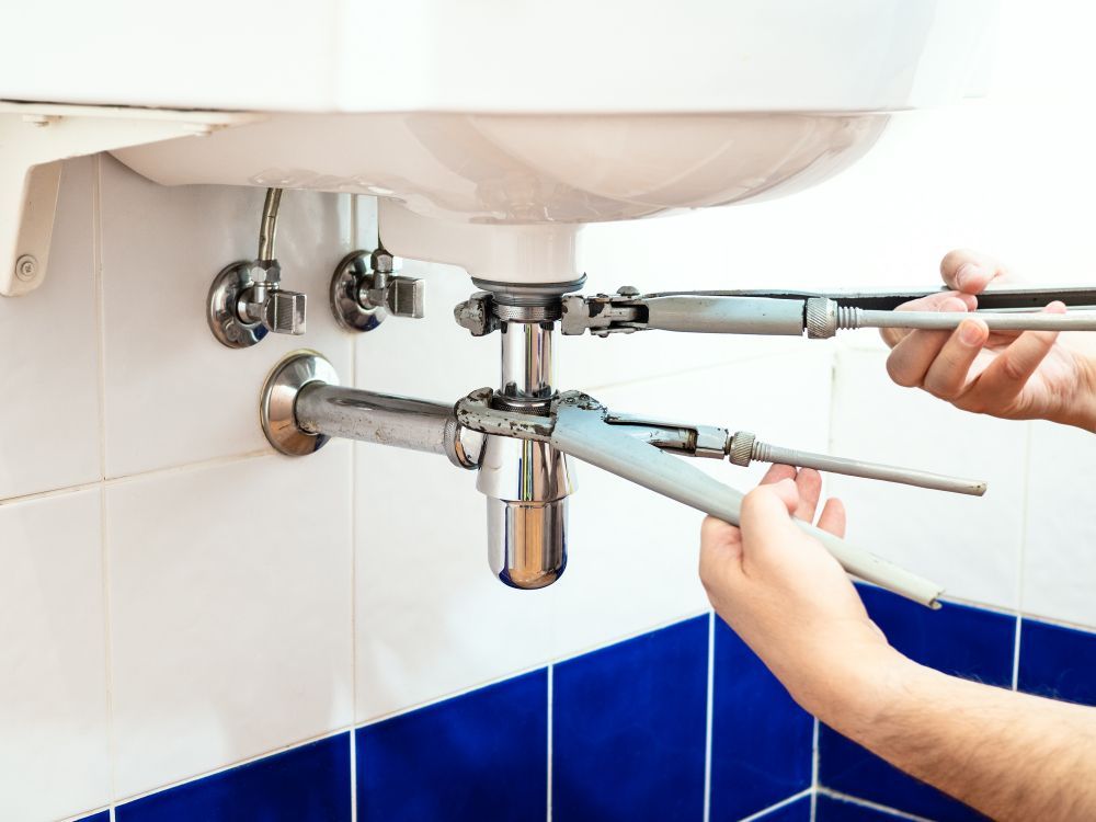 A Person is Fixing a Sink With a Wrench — Subat Plumbing Services in Cessnock, NSW