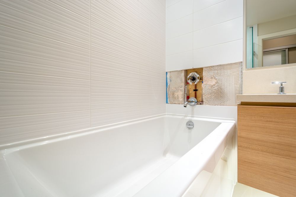 A Bathroom With a Bathtub, Sink and Mirror — Subat Plumbing Services in Maitland, NSW