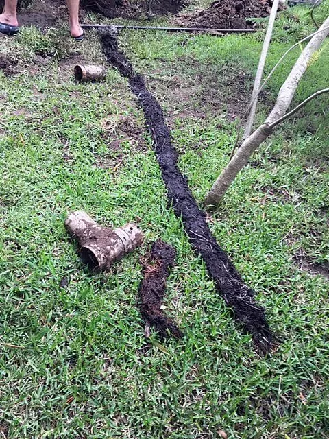 A Person is Digging a Hole in the Grass With a Shovel — Subat Plumbing Services in Kurri Kurri, NSW