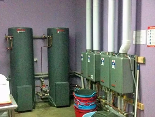 A Room With Three Water Heaters and a Red Bucket — Subat Plumbing Services in Kurri Kurri, NSW