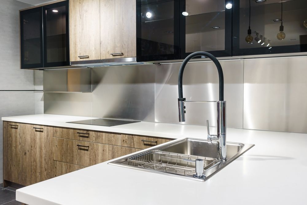 A kitchen with a stainless steel sink and a black faucet — Subat Plumbing Services in Maitland, NSW