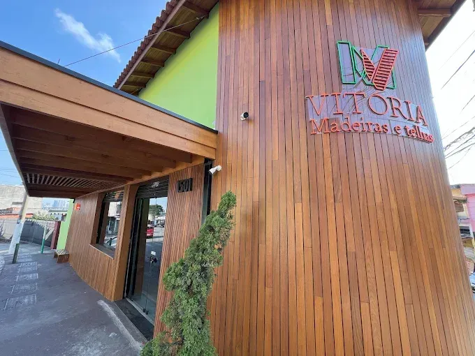 Fachada do edifício com revestimento vertical de madeira, detalhes em verde e uma placa com o nome