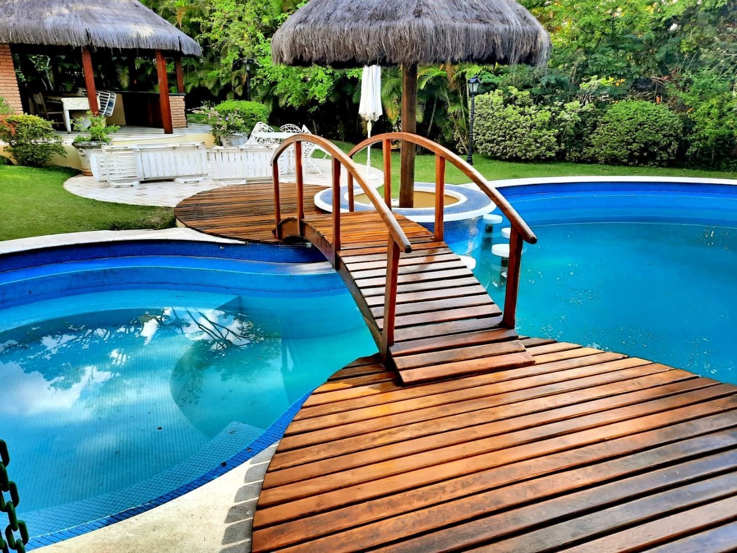 Deck de madeira da piscina com um banco ao lado de uma parede coberta de trepadeiras verdes.