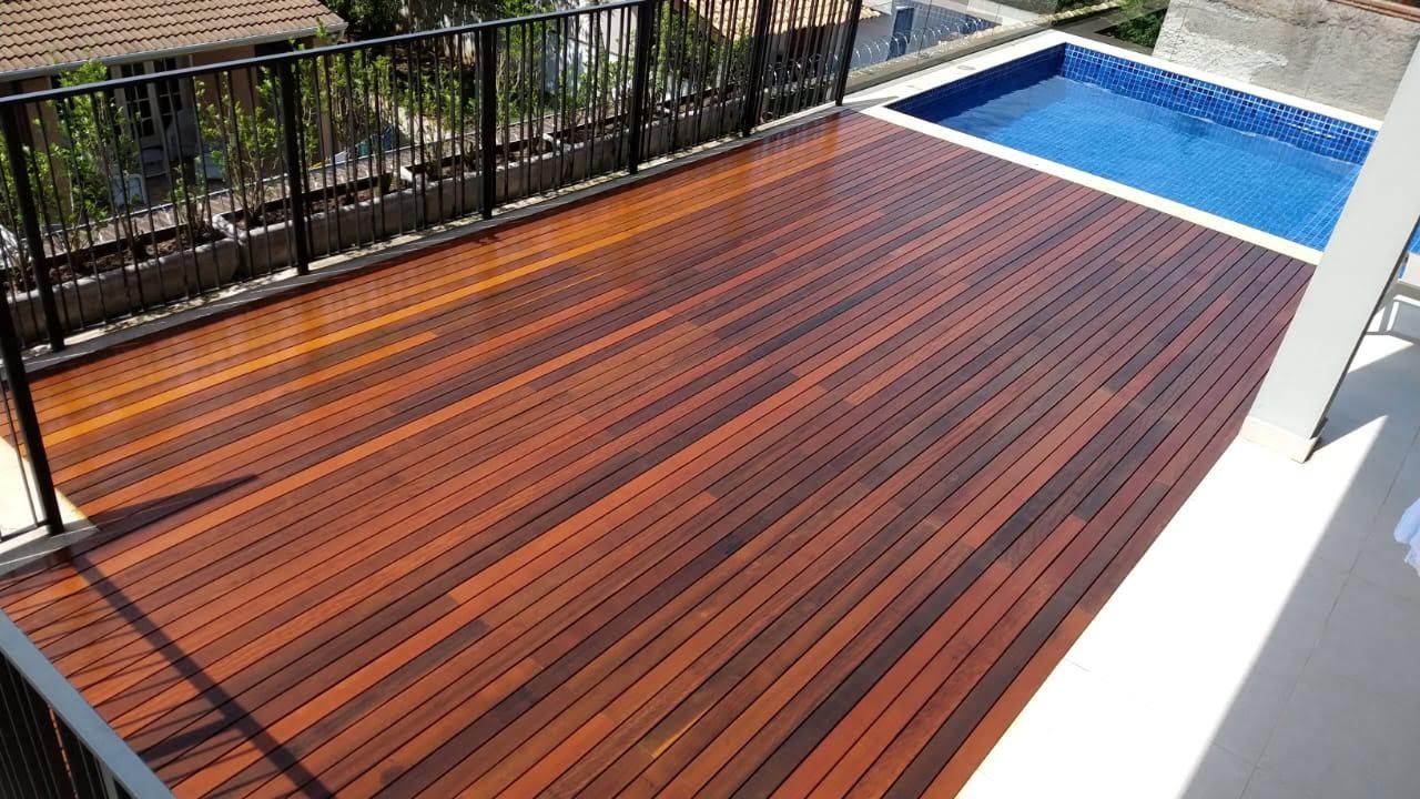 Deck de madeira com uma pequena piscina, corrimão preto, ambiente externo ensolarado.