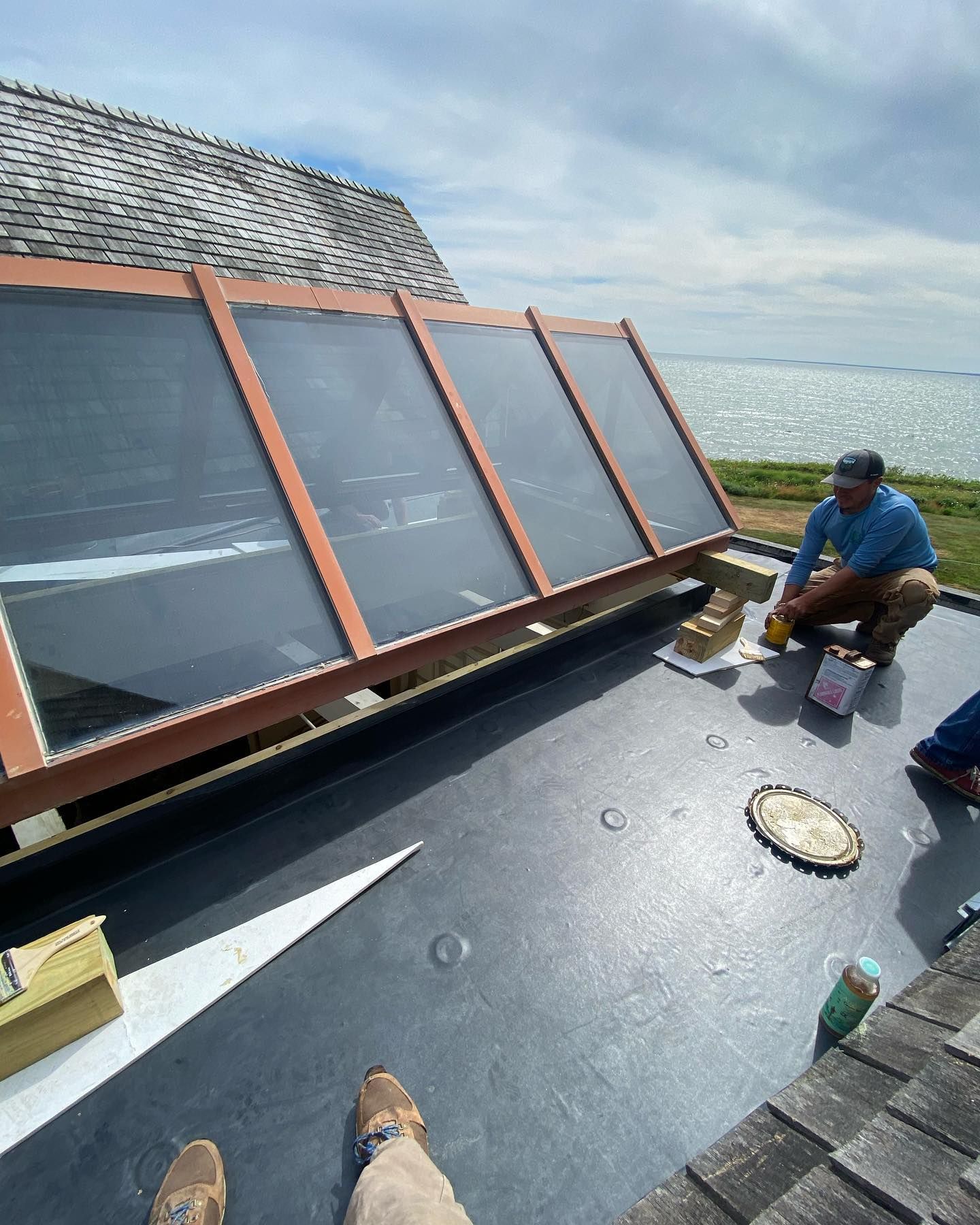 Worker installing solar panels on a rooftop beside the water.