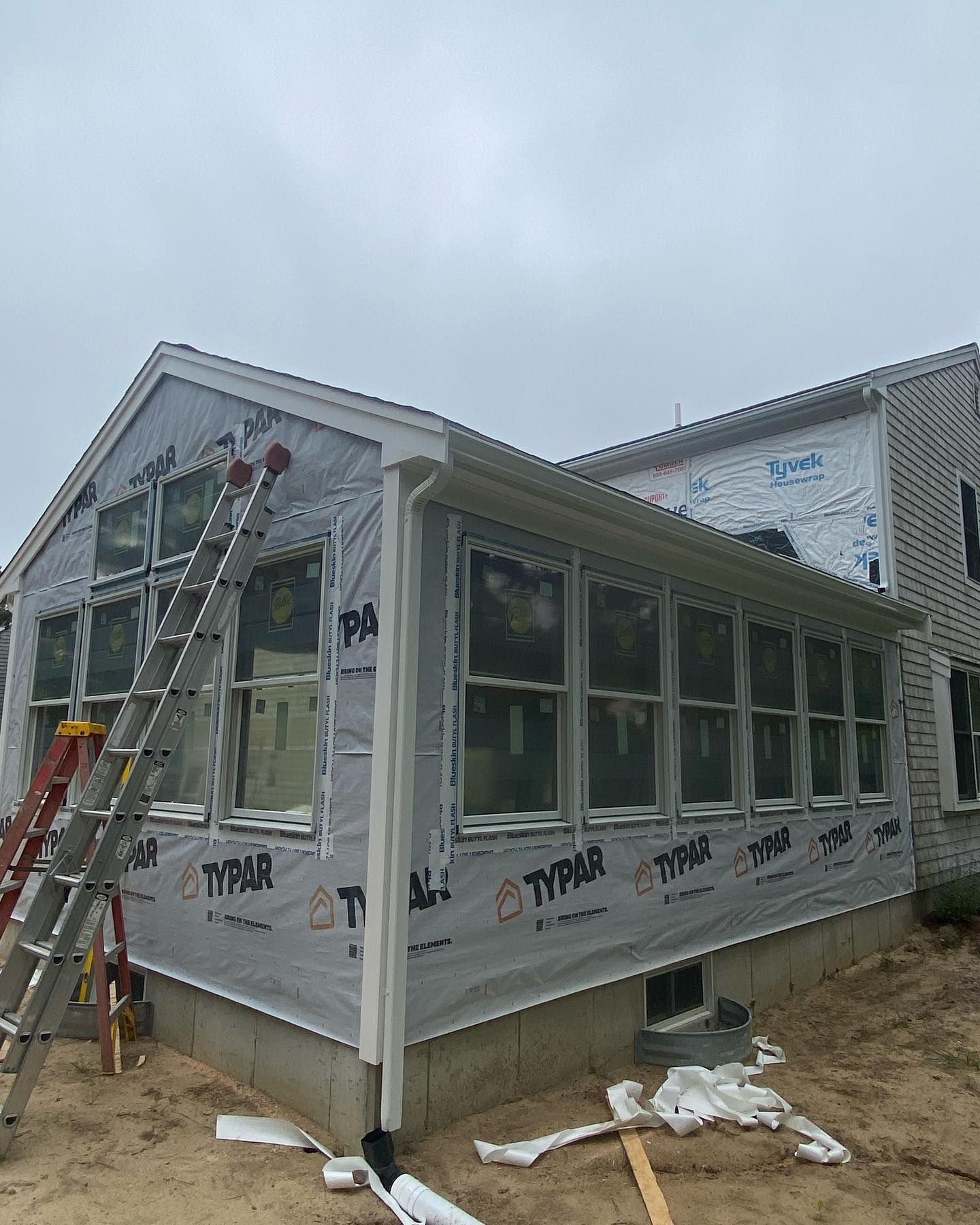 Worker on ladder installing a screened porch addition to a house under construction