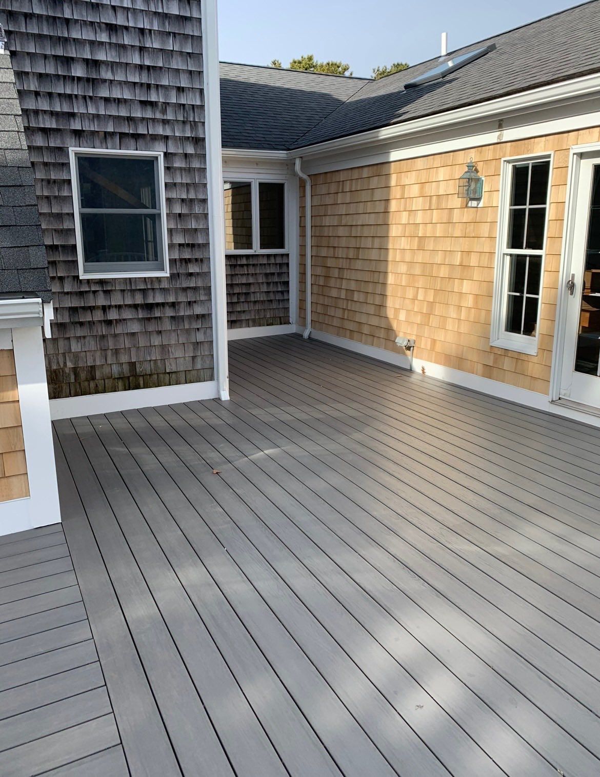 Courtyard deck with gray composite boards between weathered shingle and tan siding buildings