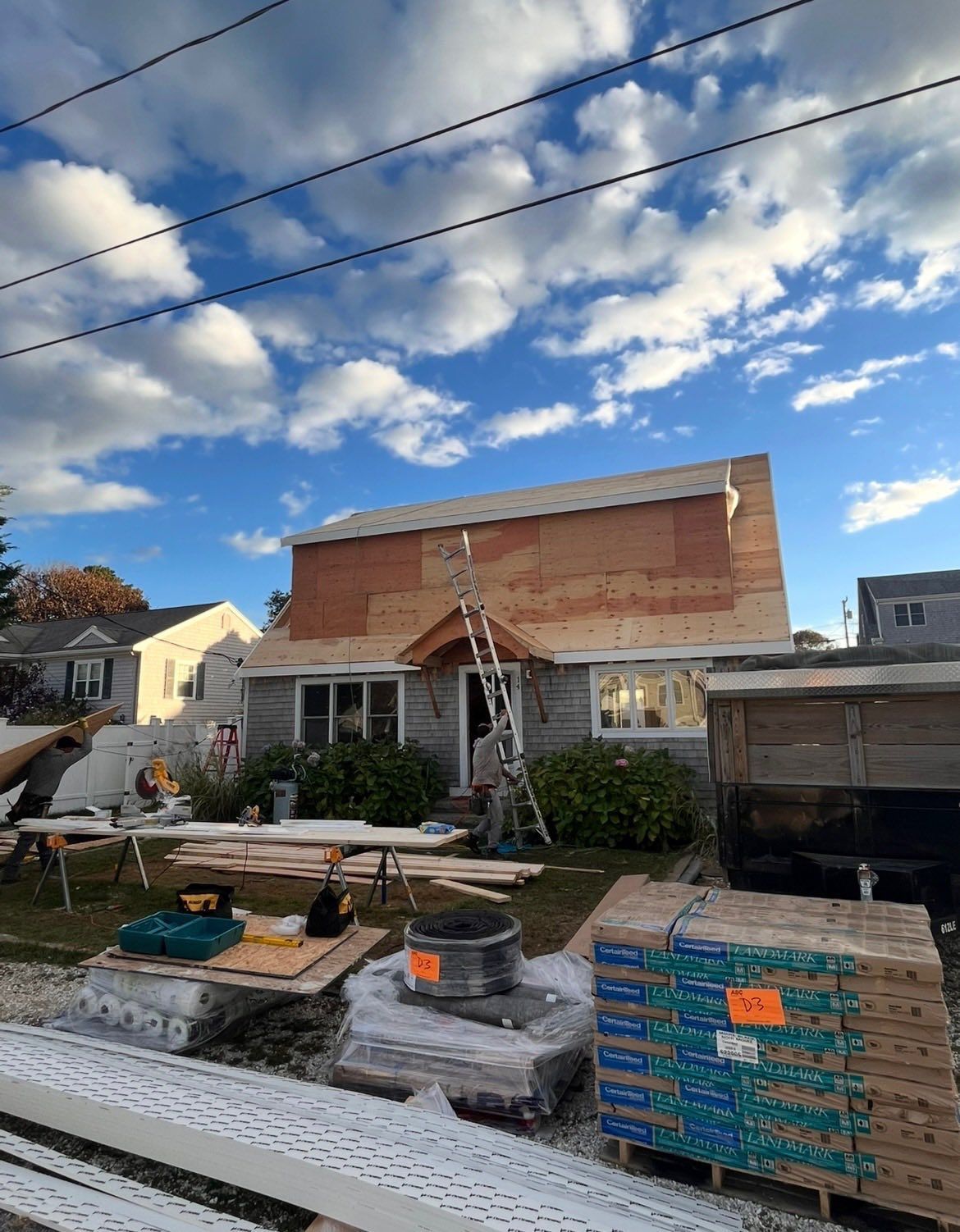 Partially built brick house with scaffolding, construction materials, and a cloudy sky overhead