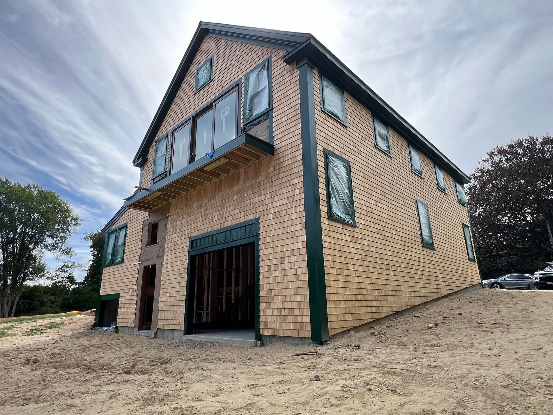 Two-story brick house with green trim and blue windows on a gravel lot