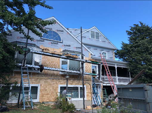 House under renovation with ladders, scaffolding, and exposed siding