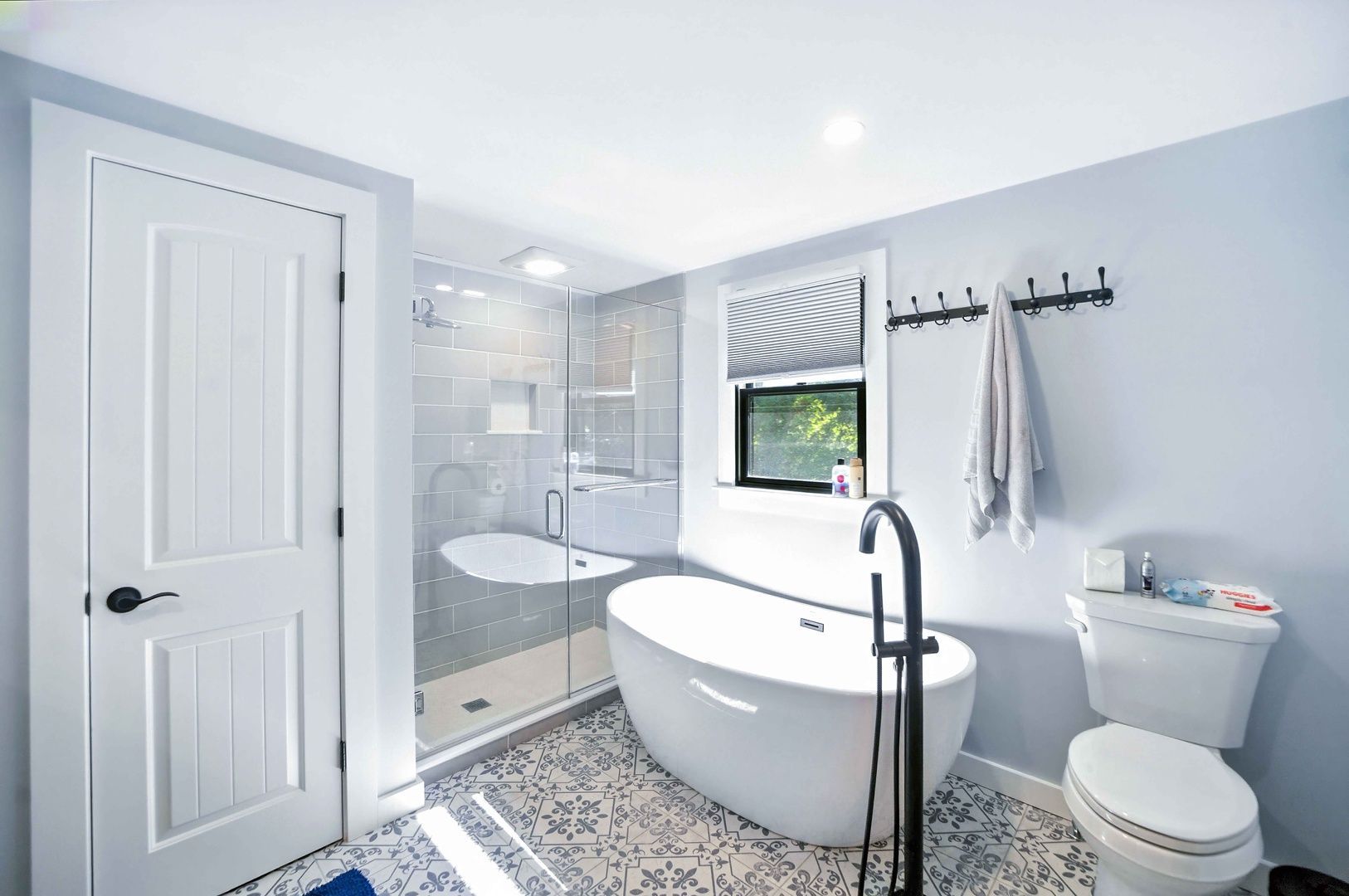 Bright modern bathroom with freestanding tub, walk-in shower, toilet, and gray-blue walls