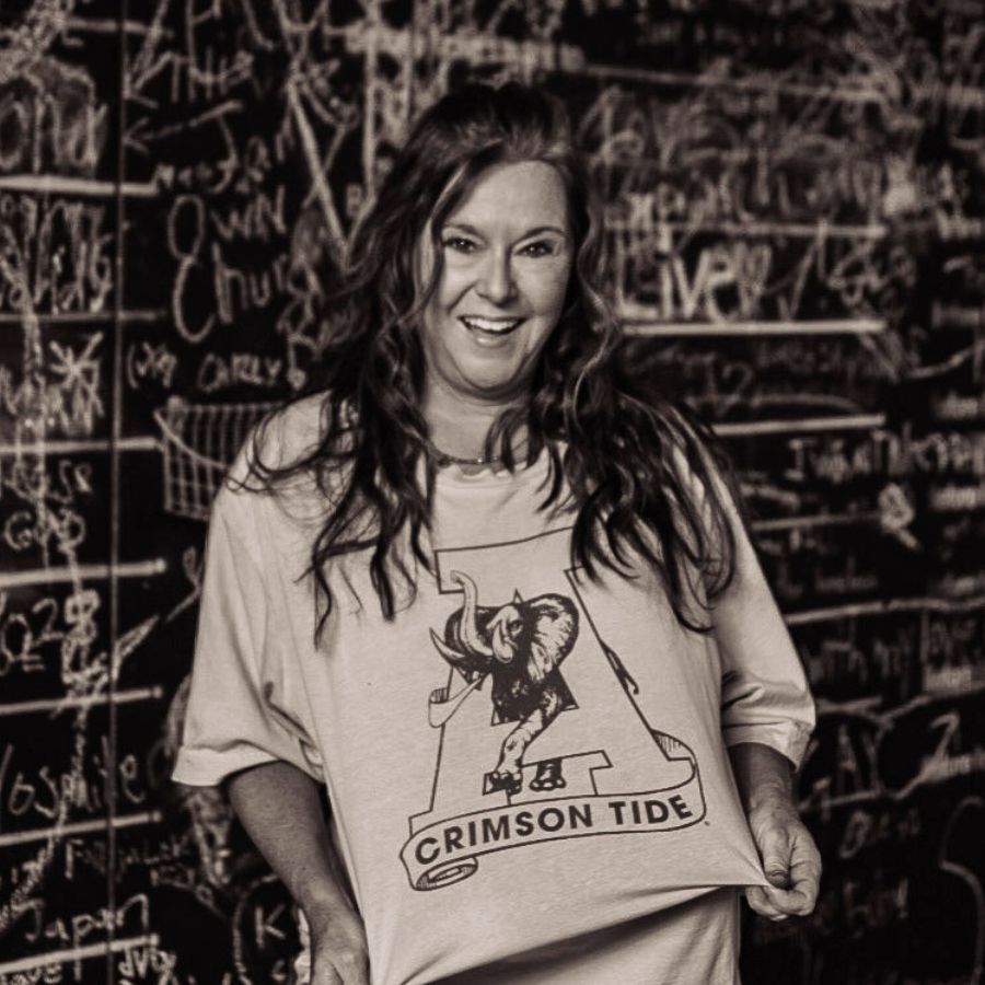 Woman smiling in a Crimson Tide shirt standing before a chalkboard covered in writing