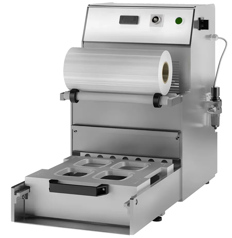 Stainless steel tray sealer machine with a roll of clear plastic film and a four-compartment mould for food packaging.