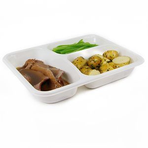 A three-compartment white tray containing sliced meat with gravy, green beans, and roasted herb potatoes.