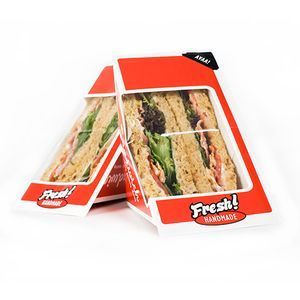 Two fresh handmade sandwiches in wedge-shaped, red and white cardboard containers with transparent plastic windows.
