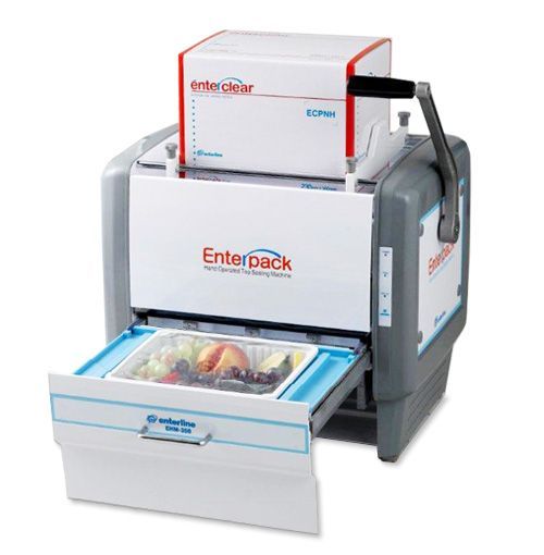 An Enterpack tray sealing machine with a tray of fresh fruit sitting in the open drawer, ready to be sealed.