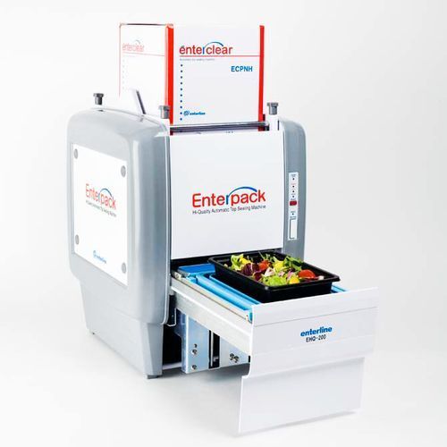 An Enterpack tray sealer machine on a white background with a container of salad on the loading tray.