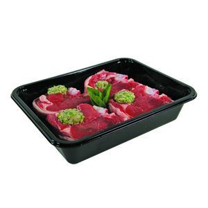 Raw lamb chops seasoned with green herbs in a black plastic food tray.