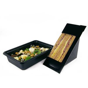 A black rectangular food container with salad next to a black triangular wedge container holding a sandwich.