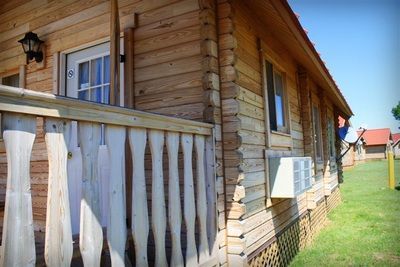 A wooden house with a white railing and a window.