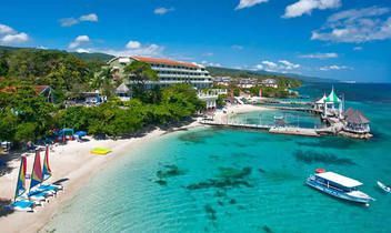 sandals ochi beach An aerial view of a beach with a boat in the water.