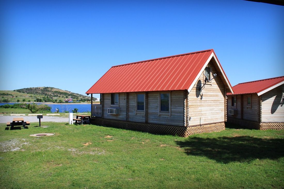 log cabin A small cabin with a red roof and a lake in the background