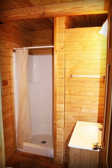 A bathroom with a shower and a sink in a log cabin.