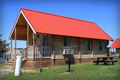 A log cabin with a red roof and a picnic table