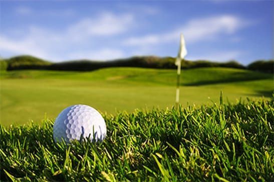 A golf ball is sitting in the grass on a golf course.