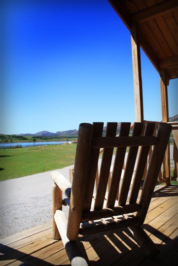A wooden chair sits on a porch overlooking a lake