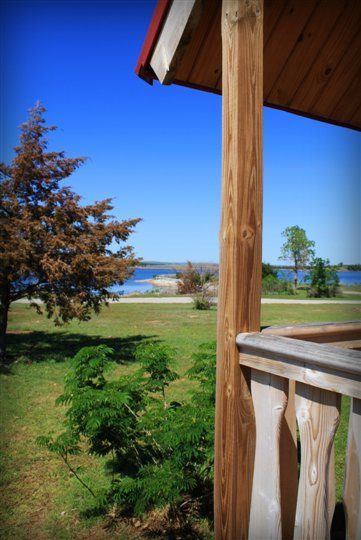 A view of a lake from a balcony with a tree in the foreground