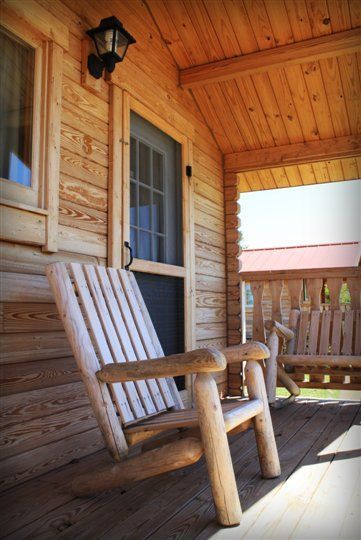 A wooden cabin with a red roof is sitting next to a lake.