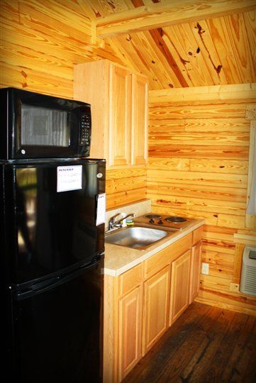 A kitchen with a black refrigerator , microwave , sink and stove.