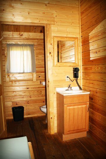 A bathroom in a log cabin with a sink , mirror and toilet.