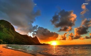 outrigger reaf beach A sunset over a beach with a mountain in the background