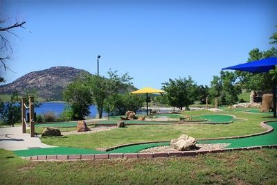 A small golf course with a blue umbrella and a mountain in the background.