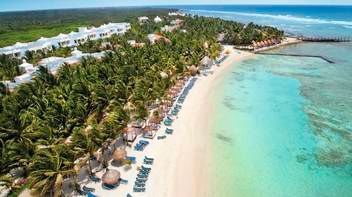 An aerial view of a tropical beach with palm trees and umbrellas.