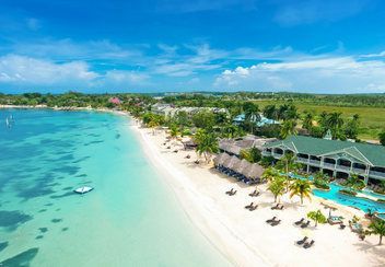 sandals negril beach resort An aerial view of a tropical beach with a hotel in the background.