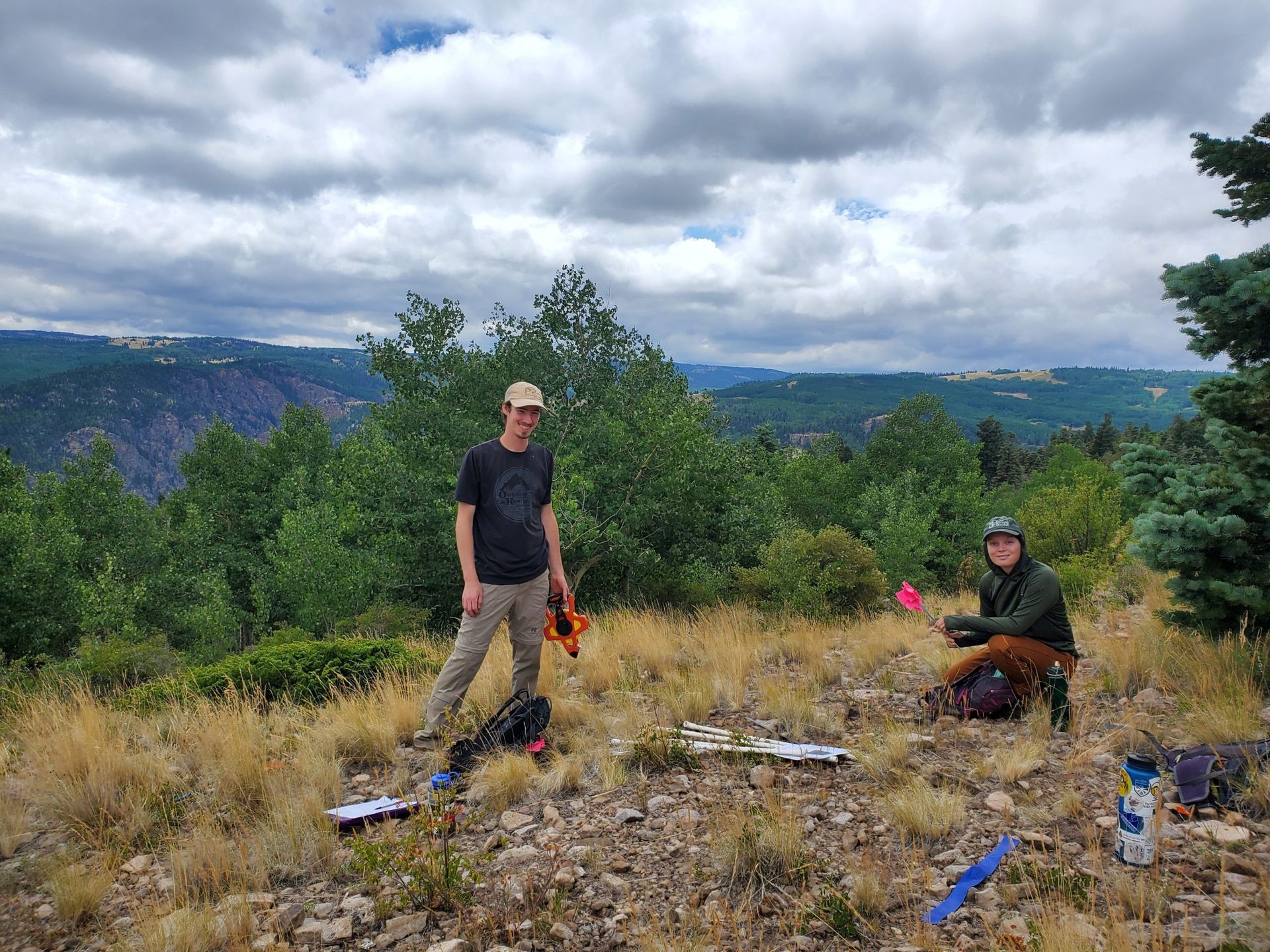 Photo of Brian with field work equipment on a high ridge forested area.