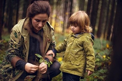 Photo of woman and child in the woods looking at a leaf
