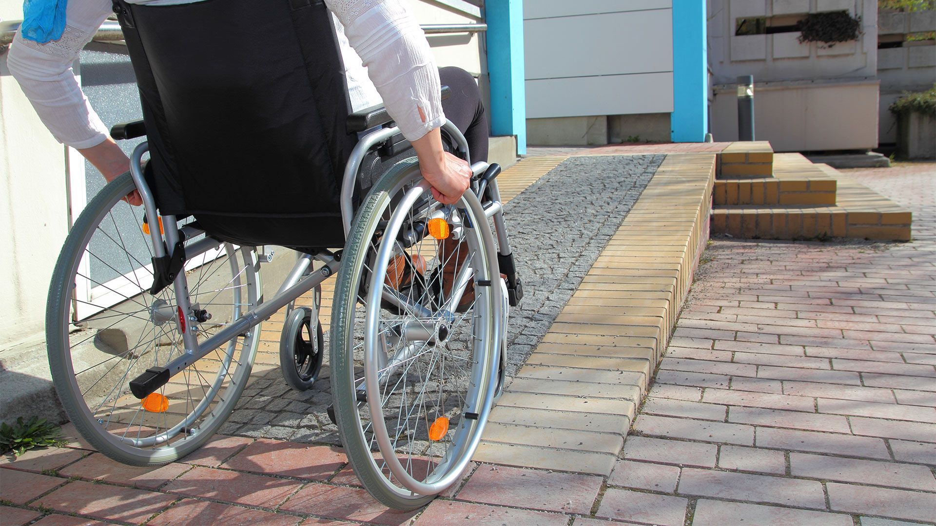 A person in a wheelchair is going down a ramp.
