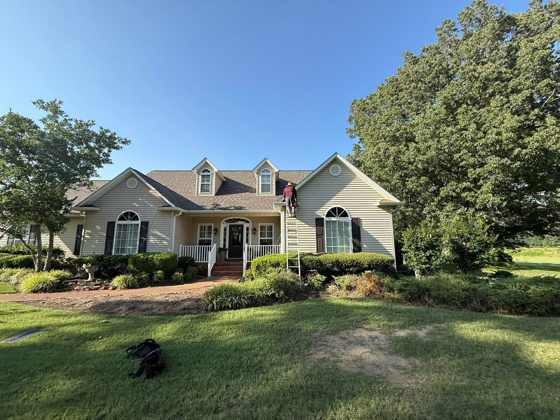Suburban house with a front porch, landscaped yard, and American flag under a clear blue sky