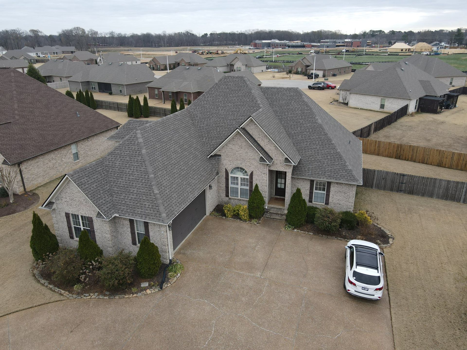 Aerial view of a gray suburban house with a gravel driveway and white car parked outside