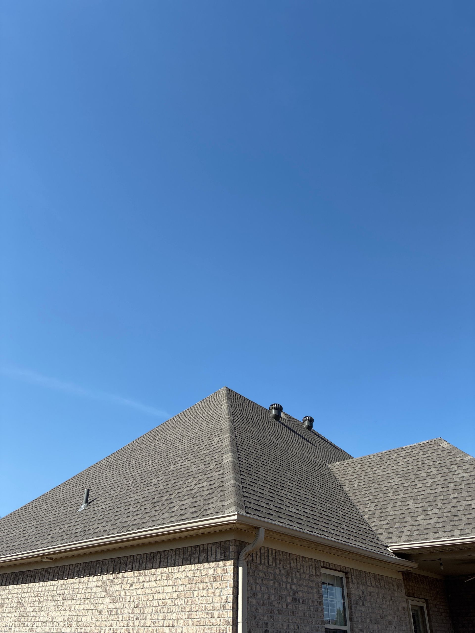 Brick house roof against a clear blue sky