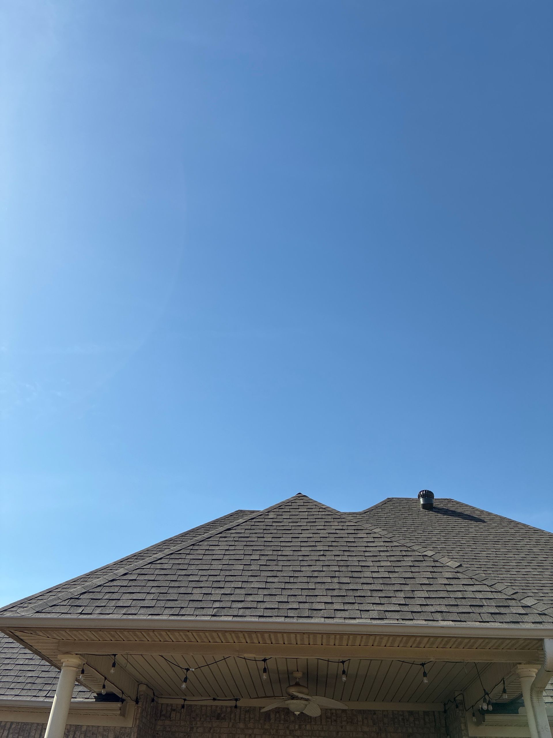 Rooftop with weathered shingles against a clear blue sky